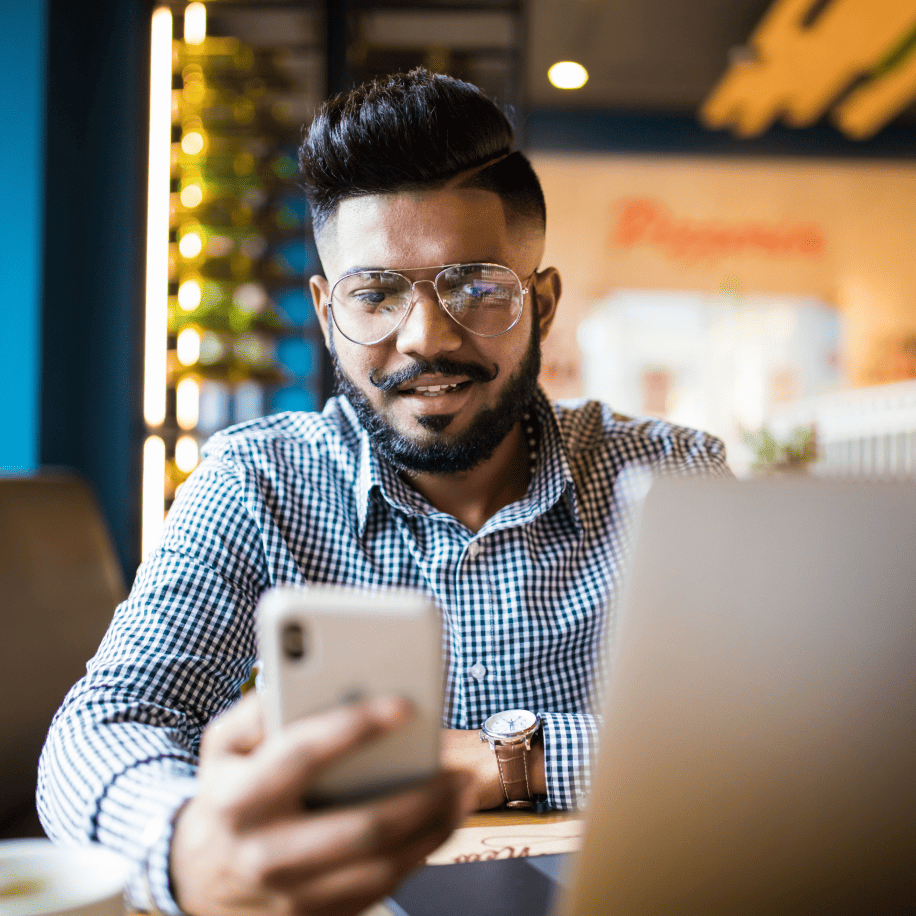 Un uomo che effettua la verifica sul suo smartphone in una caffetteria.